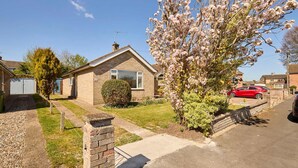 A residential house with a front yard, a driveway, and a parked red car. - Host Stay Park View (Thetford)
