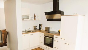 Une cuisine moderne avec des armoires blanches, une hotte en acier inoxydable, un four encastré et un plan de travail en bois.