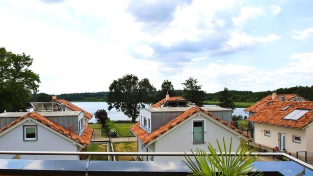 Un quartier résidentiel où les maisons se distinguent par leurs toits recouverts de tuiles rouges et offrent une vue sur un lac.