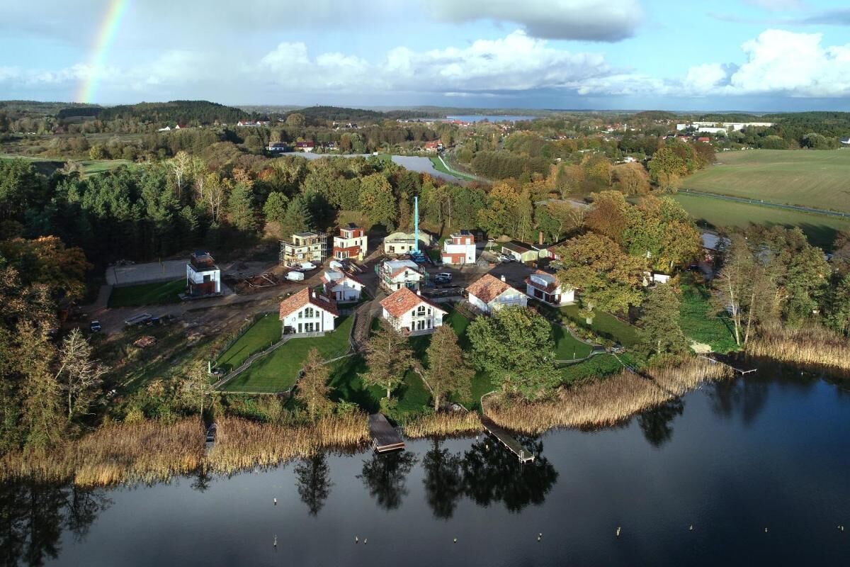 An aerial view of a lakeside village with houses, a church, and a river.