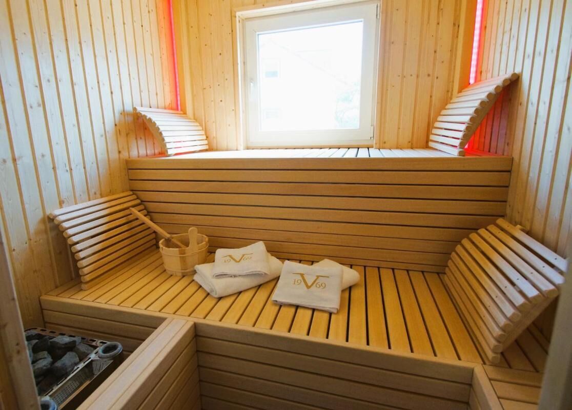 Een houten sauna met banken, handdoeken en een raam.