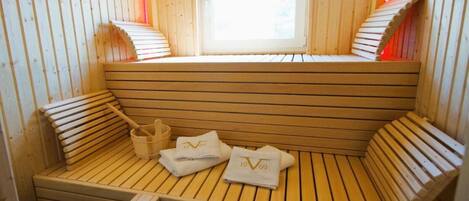 Een houten sauna met banken, handdoeken en een raam.