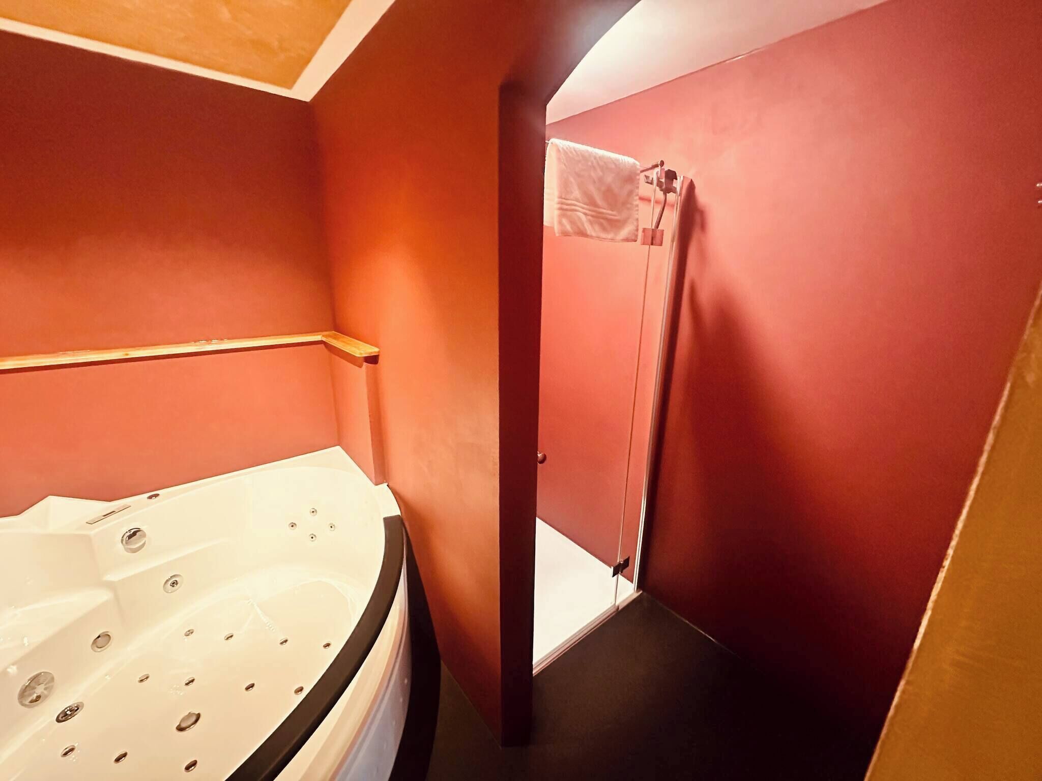 A bathroom with a bathtub, a shower curtain, and a wooden shelf.