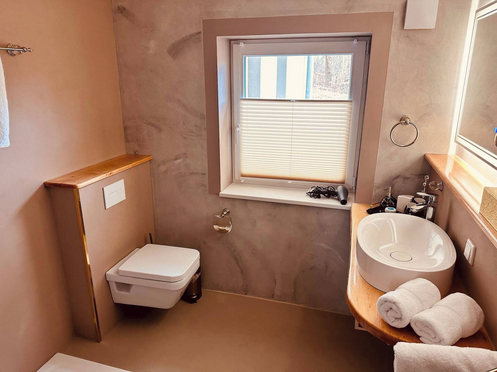 Een kleine badkamer met toilet, wastafel en raam.