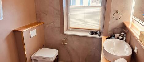 A compact bathroom with a toilet, sink, and window.