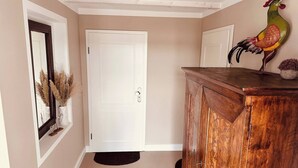 A hallway with a wooden cabinet, a white door, and a decorative rooster statue. - Weißt Du Noch- Luxus am See (Krakow am See)