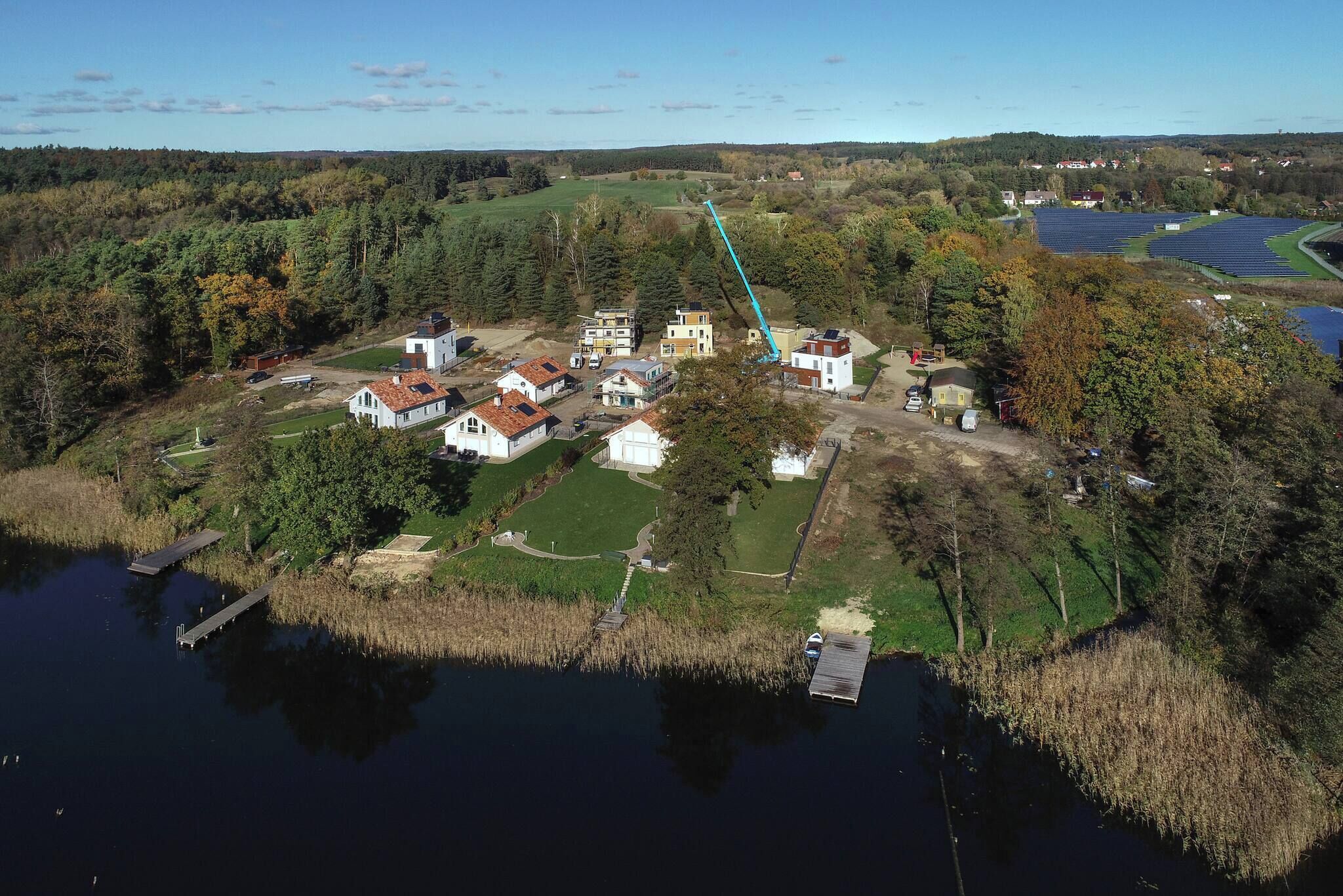 Vue aérienne d’une propriété au bord du lac, comprenant plusieurs bâtiments, un quai et un ciel dégagé.