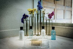 A bathroom vanity with multiple bottles of L'OCCITANE body wash and a clear soap dish.
