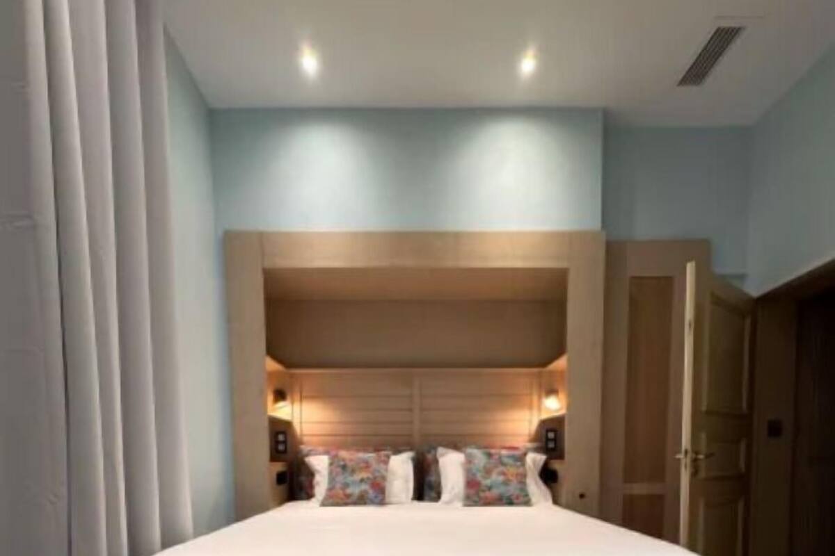 Una camera da letto moderna con un grande letto, una testiera in legno e un pavimento piastrellato.