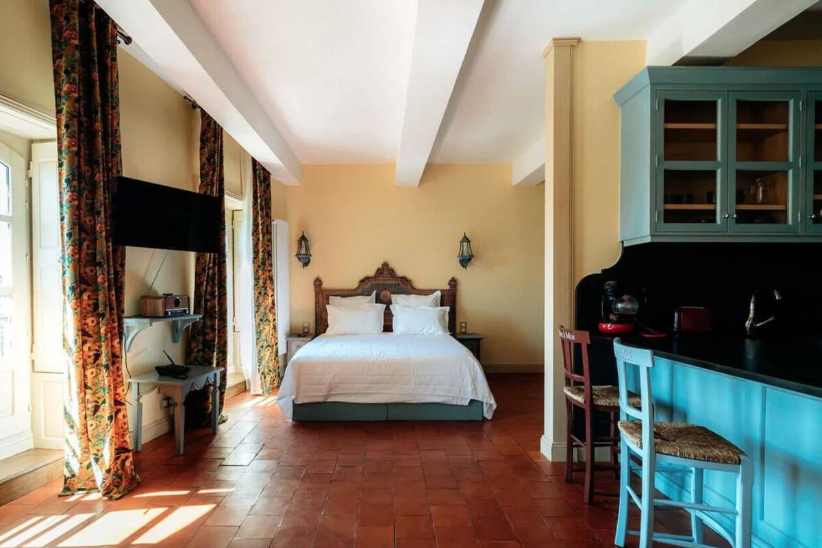 Una camera da letto con un letto, un comodino, una cassettiera e un angolo bar.
