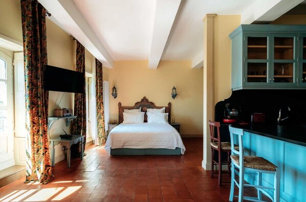A bedroom with a bed, a nightstand, a dresser, and a bar area.