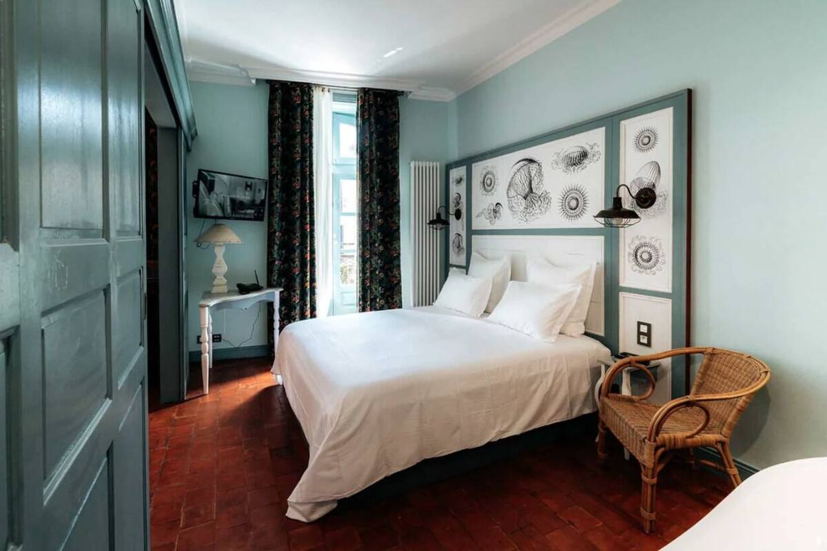 Una camera da letto con un letto, una sedia, una lampada e opere d'arte alle pareti.