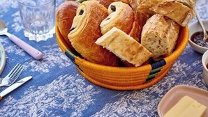 A breakfast setting with pastries, fruits, and a bottle of orange juice on a table. - The Suite (Valliguières)