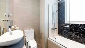Un baño moderno con lavamanos, inodoro y ducha blancos.