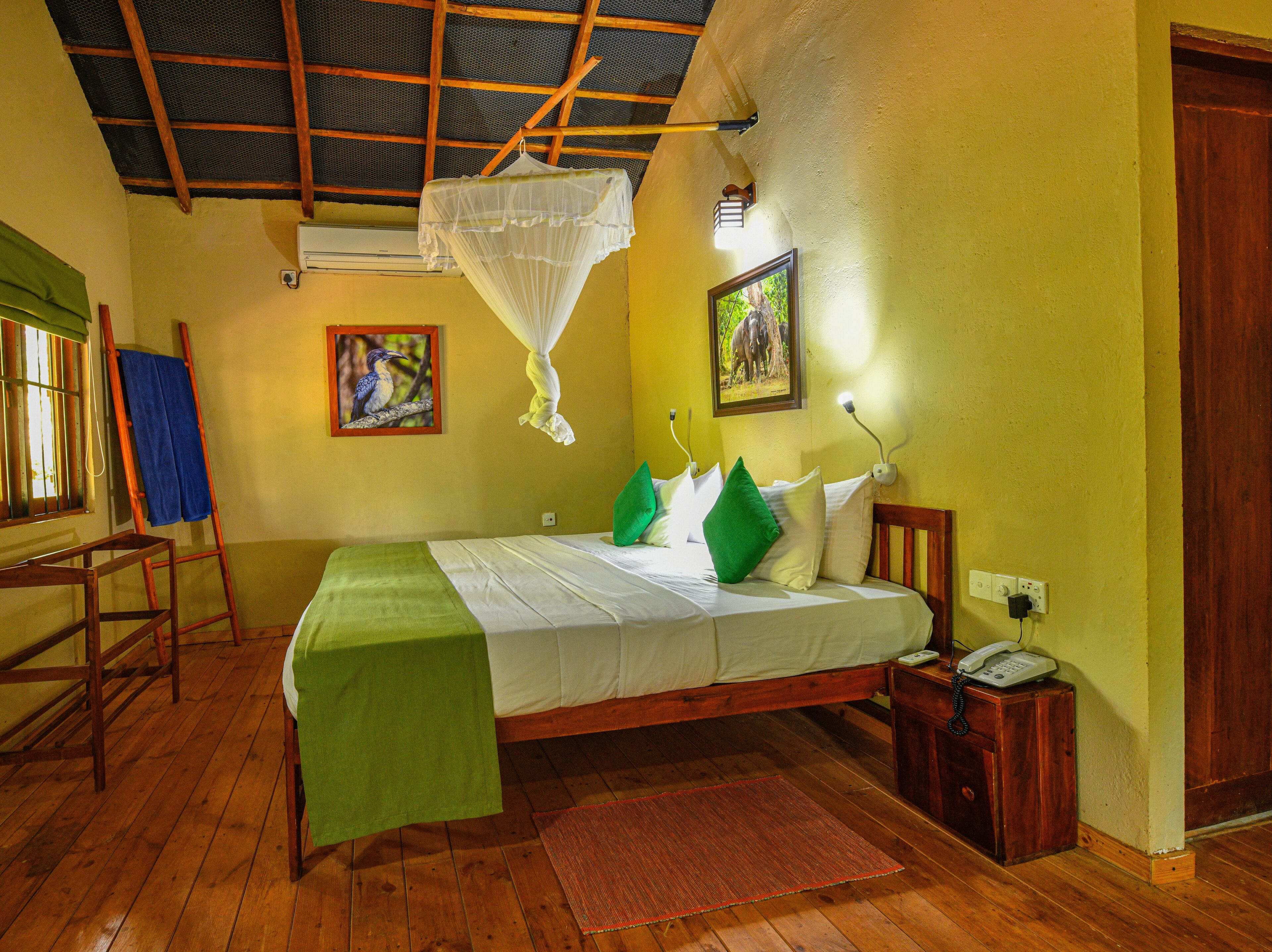 Een kamer met een bed, een ventilator, een houten ladder, een groene mat en een wandlamp.