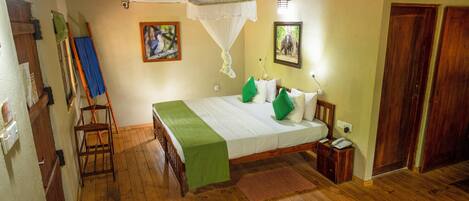 A wooden-floored bedroom with a bed, a standing fan, and a wall-mounted air conditioner.