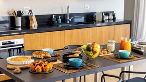 Een moderne keuken met een zwart aanrecht, houten kastjes en een eethoek met ontbijtartikelen.