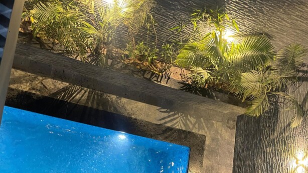 An indoor swimming pool with a clear blue water surface, surrounded by a stone wall and a wooden deck.