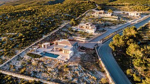 Ett flygbildsbild av ett bostadsområde med flera hus, en swimmingpool och en väg.