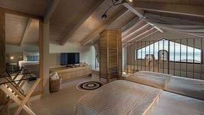A modern bedroom with a large bed, a small desk, and a view of the sea. - Terra Lucis Mountain Residences (Zakynthos)