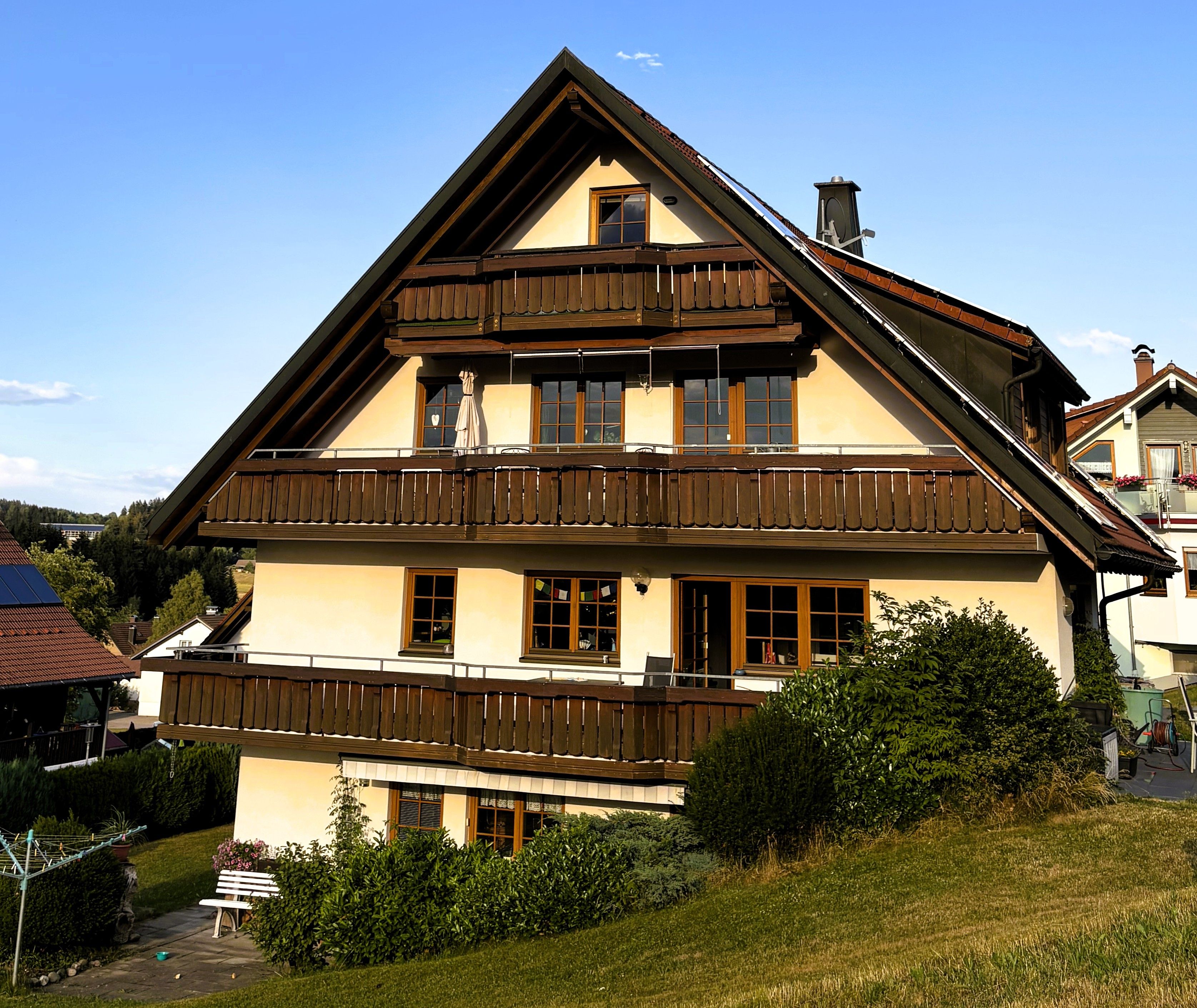 Eine zweistöckige Chalet mit Balkon, großen Fenstern und einem geneigten Dach.