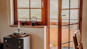Une pièce avec une fenêtre en bois, une petite table sur laquelle est posée une bougie, et une chaise.