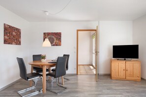 Un comedor moderno con una mesa de madera, sillas negras y dos obras de arte colgadas en la pared.