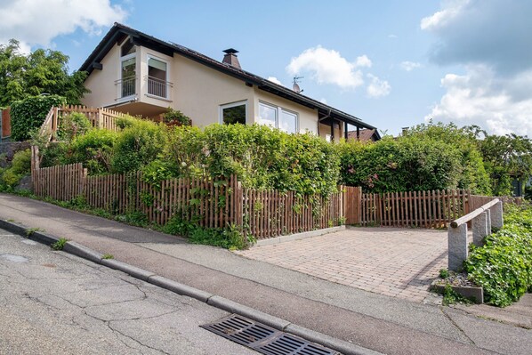 A two-story house with a paved driveway and a wooden fence.