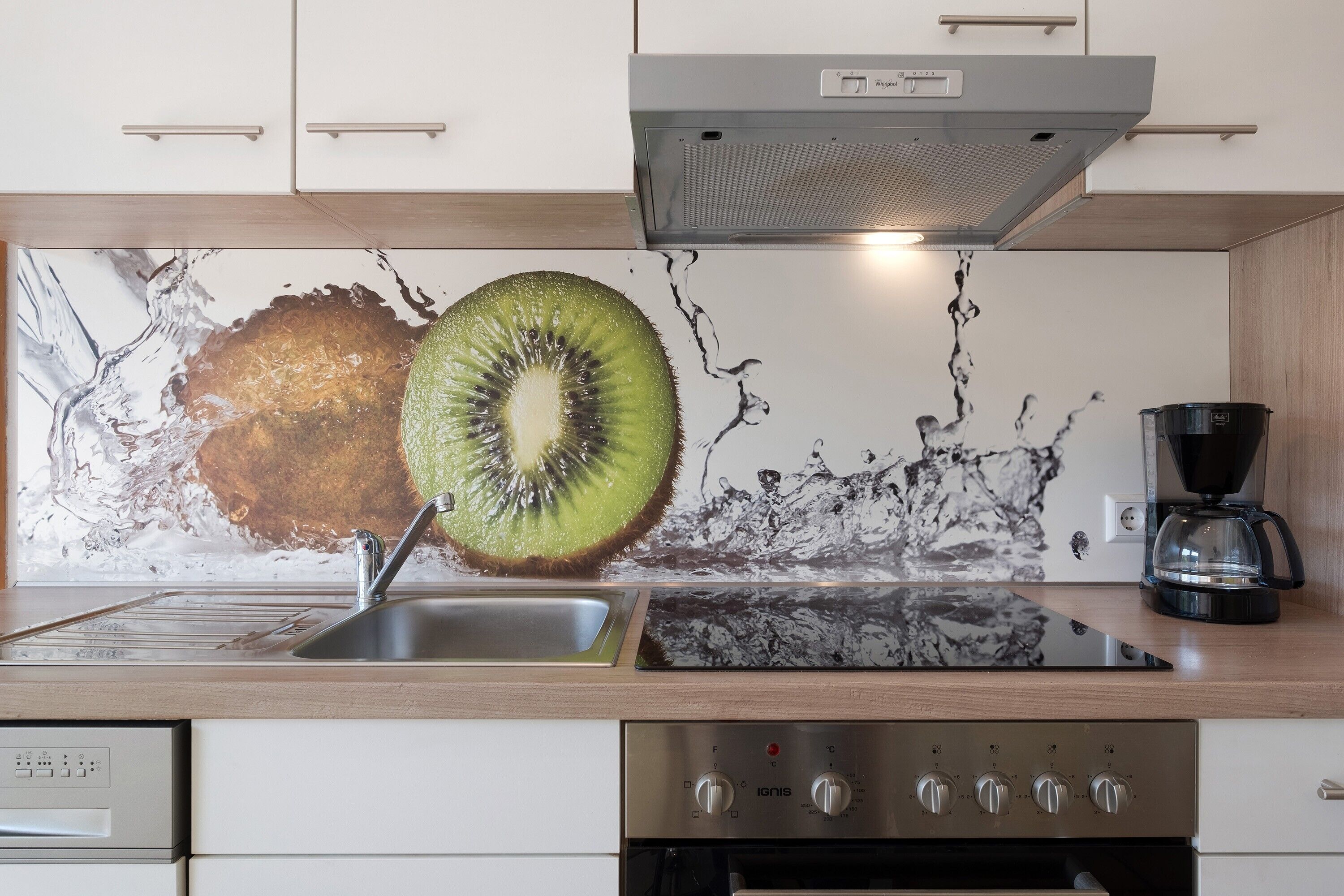 Eine moderne Küche mit einem Edelstahl-Spülbecken, einer Kaffeemaschine und einem großen Wandbild.