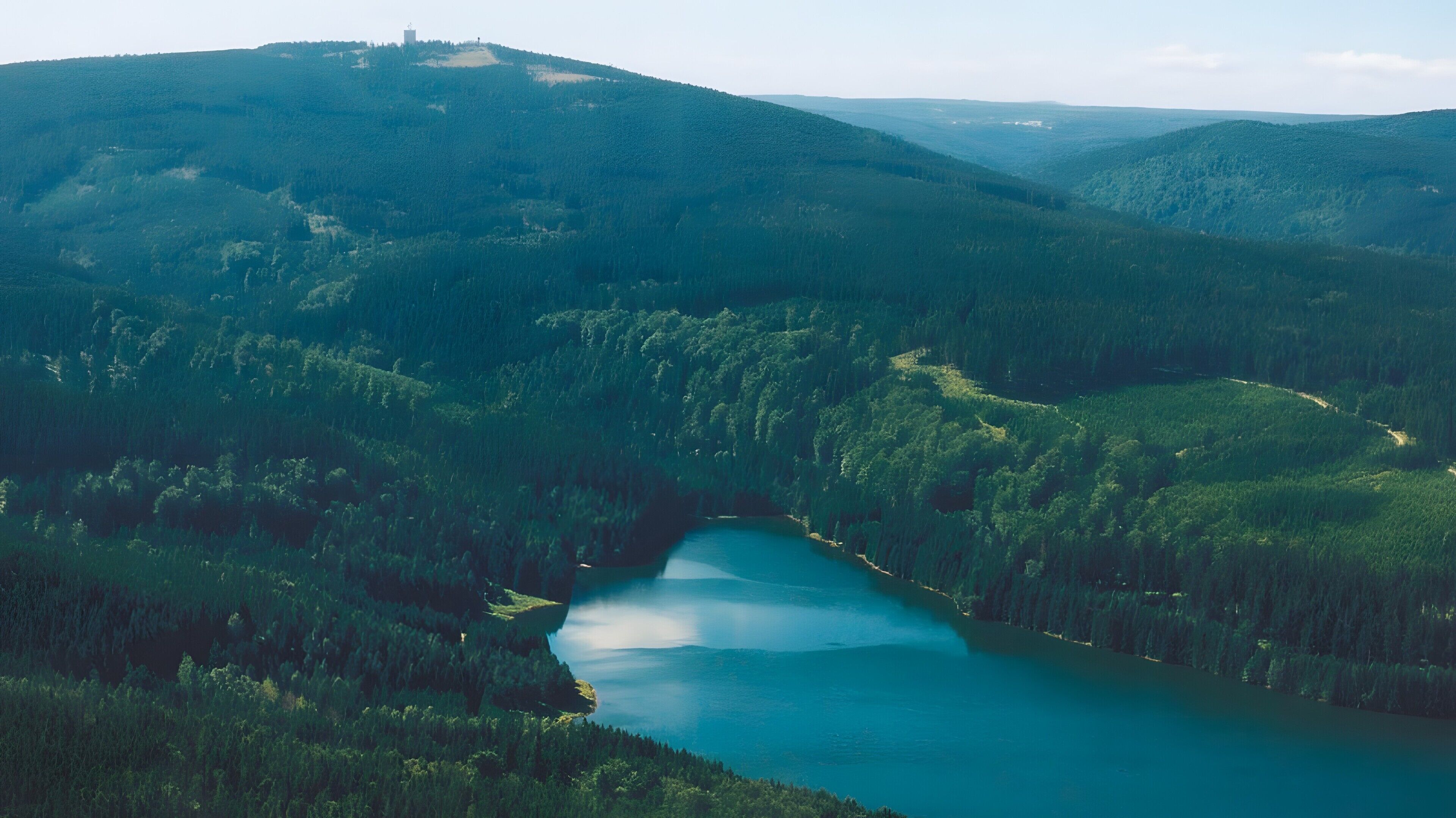 Un valle boscoso con un lago y colinas.