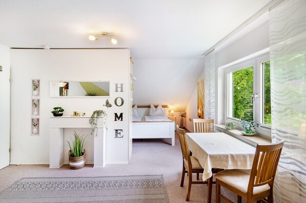 A bedroom with a bed, bedside table, and a window with curtains.