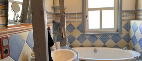 A bathroom with a freestanding bathtub, a sink, and a mirror.