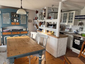 Eine Küche mit einem Holztisch, weißen Stühlen und einem blauen Schrank mit Glastüren.