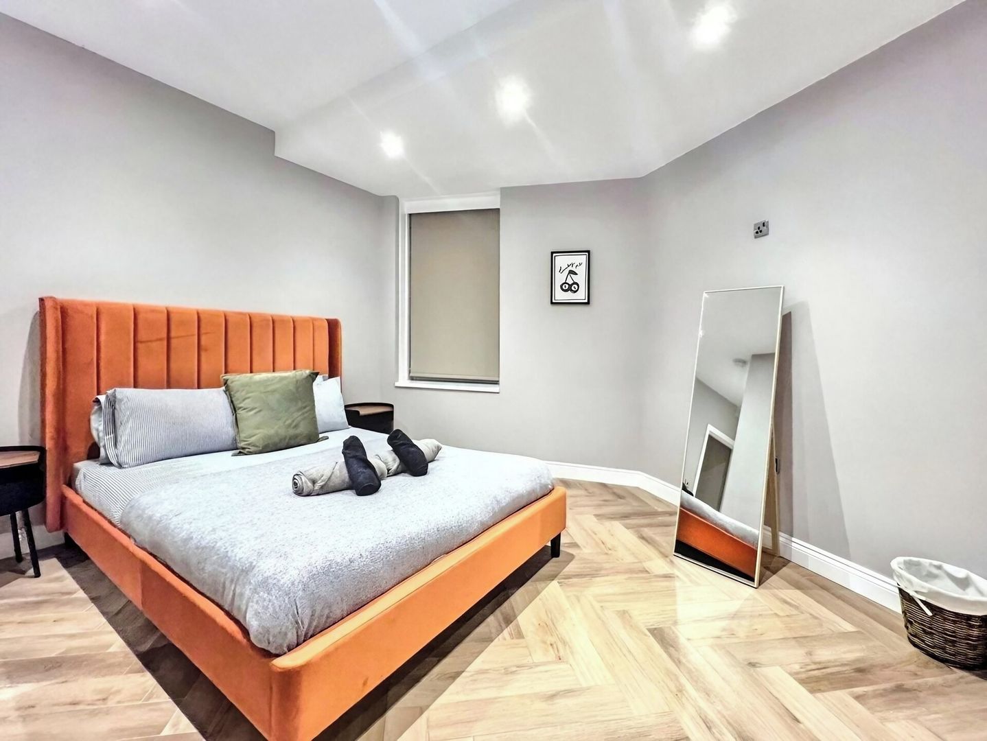 Ein Schlafzimmer mit einem Bett, einem Nachttisch, einem Spiegel und einem gerahmten Bild an der Wand.