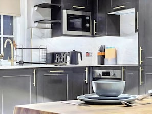 A modern kitchen with dark cabinetry, a microwave, a toaster, and a bowl on the counter.