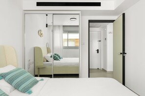 A modern bedroom with a bed, a bedside table, a wardrobe, and a door leading to another room. - Red Canyon Spa Cozy Stay by Sea N' Rent (Eilat)
