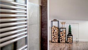 En hall med en modern inredningsstil, med bland annat ett trägolv, en öppen spis med metallram och ett dekorativt träd.