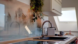 Ett modernt kök med en diskho i rostfritt stål, en inbyggd ugn och ett fönster ovanför diskhon.