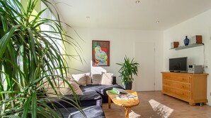 Un salon comprenant un canapé, une table basse, un téléviseur et des objets de décoration.