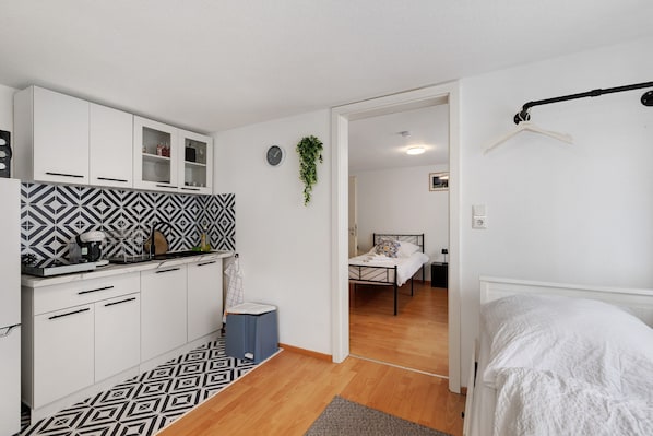 A compact room with a kitchenette, a bed, and a small bathroom.