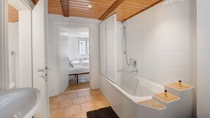 Une salle de bain moderne avec une baignoire, une douche et des murs recouverts de carreaux blancs.