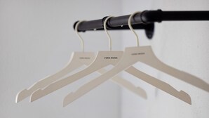 Trois cintres blancs portant l’inscription « VERO MODA » sont suspendus à une tringle noire.