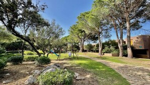 A park with a playground, stone pathway, and trees. - Cosy apartment in Olbia (Olbia)