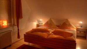 A bedroom with a bed, a nightstand, a lamp, and a window with curtains.