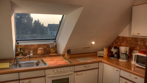 A kitchen with a skylight, a stove, a microwave, and a coffee maker.