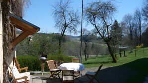 Un patio con mesa y sillas, una parrilla y vistas a un paisaje montañoso.
