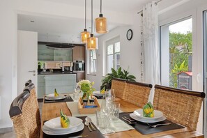 Un coin repas avec des chaises en osier, une table en bois et des lampes suspendues.