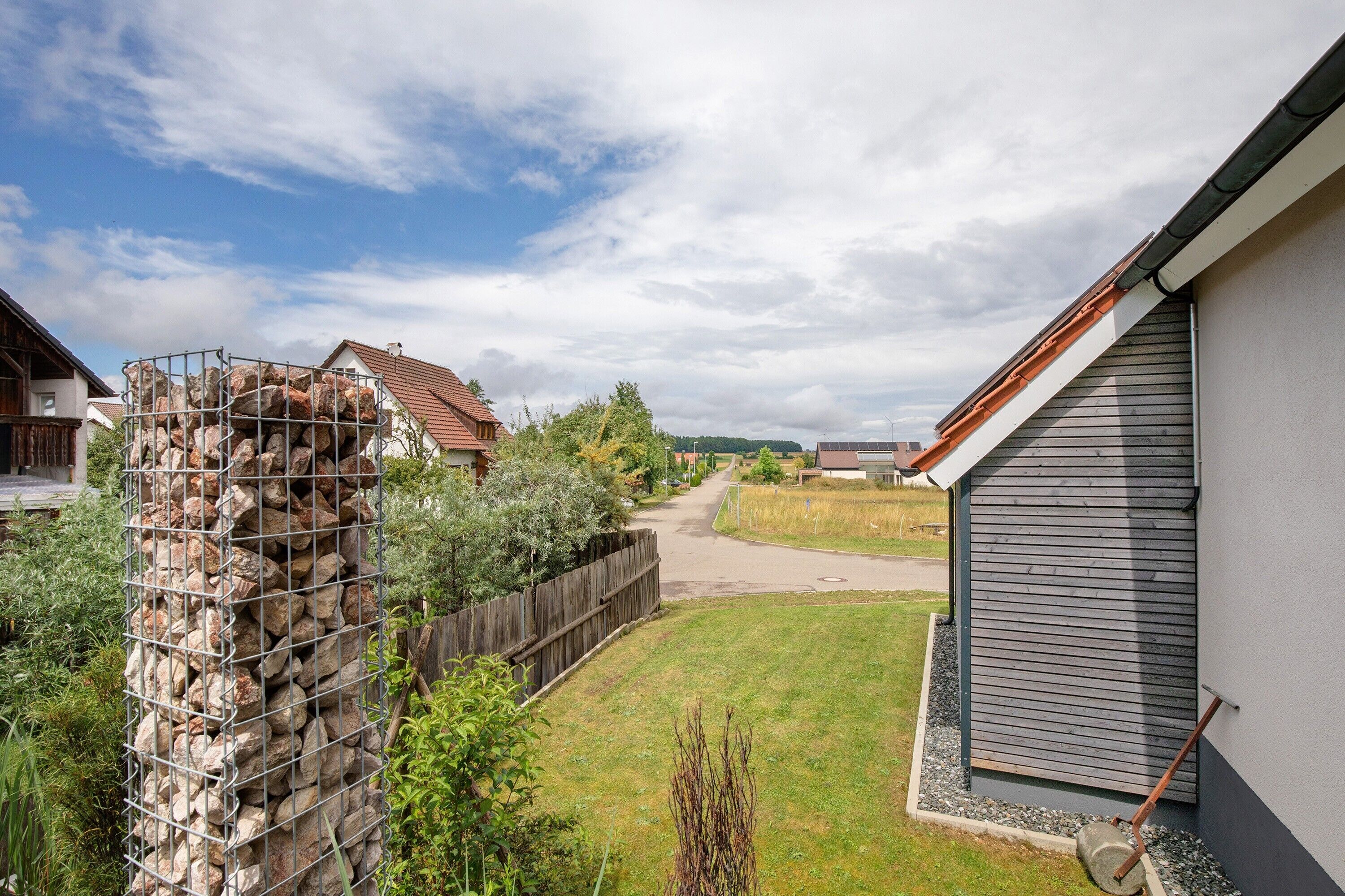 A residential area with a house, a fenced garden, and a clear sky.