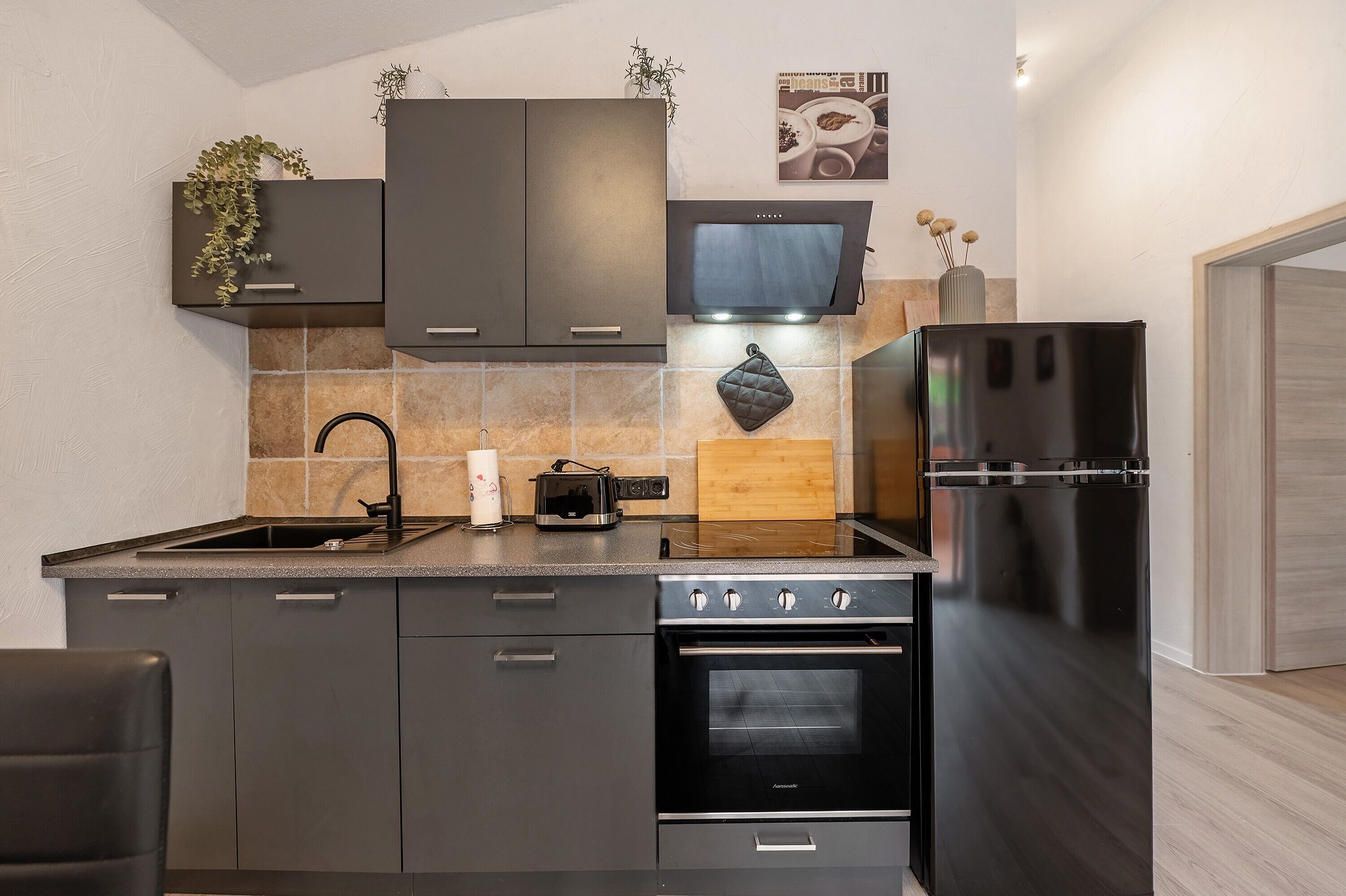 Een moderne keuken met donkere kastjes, een inbouwoven, een koelkast en een magnetron.