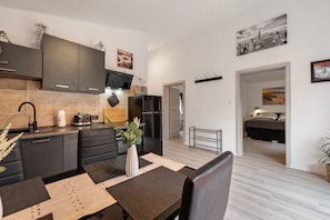 A modern kitchen with dark cabinets, a built-in oven, and a dining area with a table and chairs.